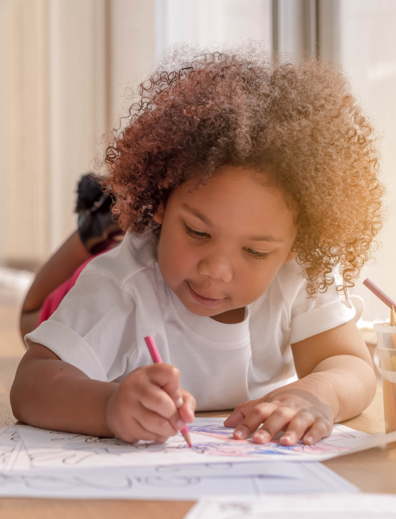 Little toddler girl laying down concentrate on drawing