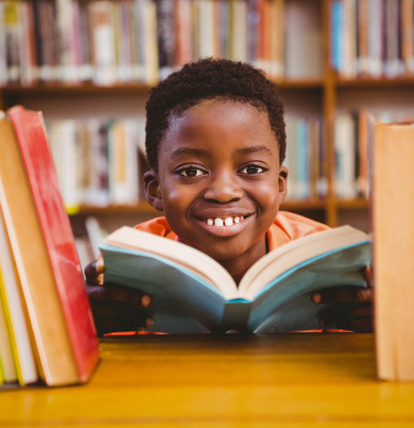 kid smiling while holding a book